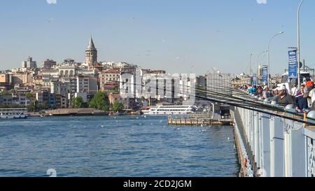 ISTANBUL, TÜRKEI - 23. MAI 2019: Menschenmenge von Fischern auf der galata-Brücke mit galata-Turm in der Ferne Stockfoto