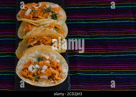 Mexikanische Tacos de Tinga, authentische Tacos mit mariniertem Fleisch, auf einem traditionellen textilen Hintergrund Stockfoto