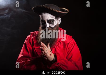 Mann verkleidet wie ein gruseliger mittelalterlicher Pirat über schwarzem Hintergrund für halloween. Stockfoto