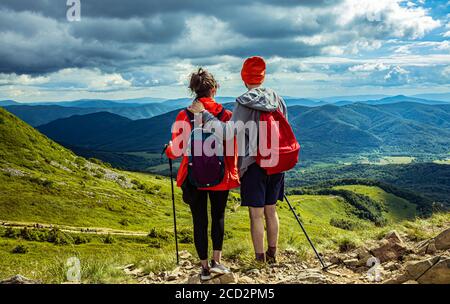Ein paar Wanderer bleiben auf der Spitze des Hügels in den Bergen. Stockfoto