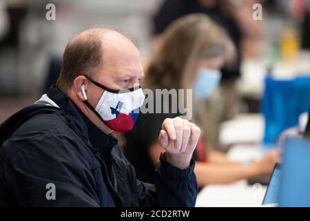 Austin, Texas, USA. August 2020. Ein Staatsbeamter arbeitet mit einer texanischen Gesichtsmaske, während Gouverneur Greg Abbott (nicht gezeigt) die Presse über die Vorbereitungen von Texas auf den Hurrikan Laura informiert, der am Donnerstag im Osten von Texas und an der Küste von Louisiana landen soll. Abbott mobilisierte Hunderte von staatlichen Ressourcen, da Texaner sich an die extremen Schäden erinnern, die der Hurrikan Harvey 2017 angerichtet hatte. Quelle: Bob Daemmrich/ZUMA Wire/Alamy Live News Stockfoto