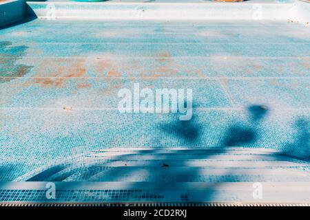 Blauer alter Pool, trocken und schmutzig am Boden. Speicherplatz kopieren. Blick von der Treppe. Konzept der Wartung und Reinigung von Schwimmbädern. Stockfoto