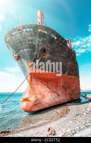 Ein altes schwarz-rotes Schiff, das ankerte und auf Grund lief. Der Bug des Schiffes aus der Nähe. Blick vom Bug des Schiffes. Blaues Meer und Himmel auf dem Hintergrund Stockfoto