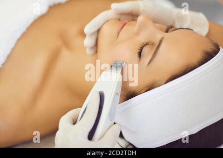 Hände von Kosmetologen machen Ultraschall Gesichtsreinigung mit speziellen Maschine Für entspannende Frau Stockfoto