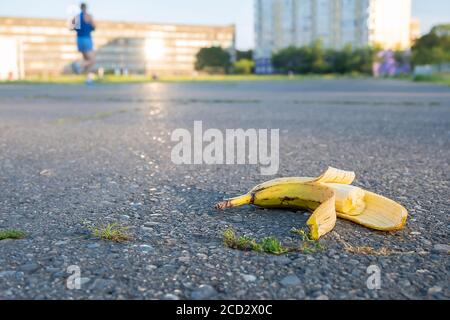 Auf der Laufstrecke des Stadions, an dem Athleten vorbeilaufen, liegt eine ausrangierte gebissene Banane Stockfoto