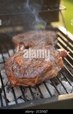 Gruppe gegrillte Ribeye Beef Steaks auf dem Grill im Freien, Hintergrund. Grill Saison Konzept, bbq Kopie Raum, Sommer Stockfoto