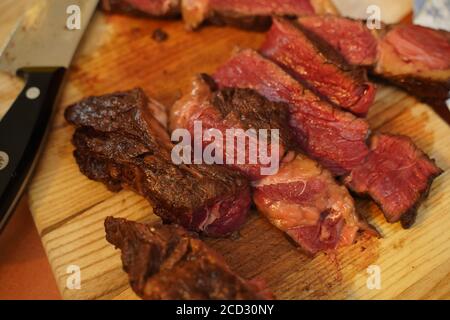 In Scheiben geschnitten Medium selten gegrilltes Rindersteak Ribeye auf Schneidebrett auf Holzhintergrund Stockfoto