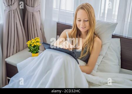 Frau zeichnet auf Tablet mit Stift im Bett Stockfoto