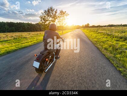 Dunkle Motorradfahrer Reiten High Power Motorrad in der Natur mit schönen Sonnenuntergang Licht. Reisen und Transport. Freiheit beim Motorradfahren Stockfoto