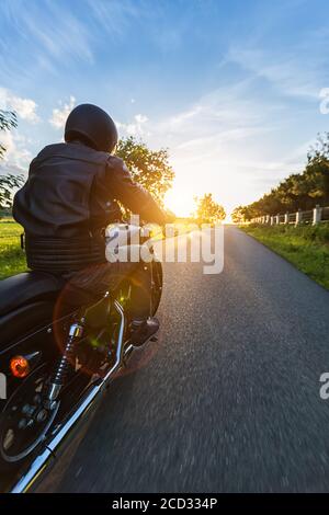 Dunkle Motorradfahrer Reiten High Power Motorrad in der Natur mit schönen Sonnenuntergang Licht. Reisen und Transport. Freiheit beim Motorradfahren Stockfoto