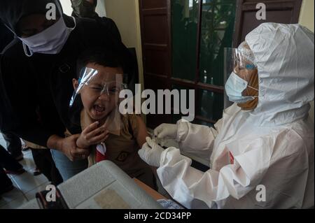 (200826) -- JAKARTA, 26. August 2020 (Xinhua) -- ein Grundschüler erhält einen Masern-Röteln-Impfstoff (MR), der von einem Gesundheitsbeauftragten während des COVID-19-Ausbruchs in Jakarta, Indonesien, am 26. August 2020 durchgeführt wird. Masern-Röteln (MR)-Impfstoffe werden Kindern als Teil des Programms der indonesischen Regierung verabreicht, um Schulkindern eine angemessene Immunisierung zu bieten. (Xinhua/Agung Kuncahya B.) Stockfoto