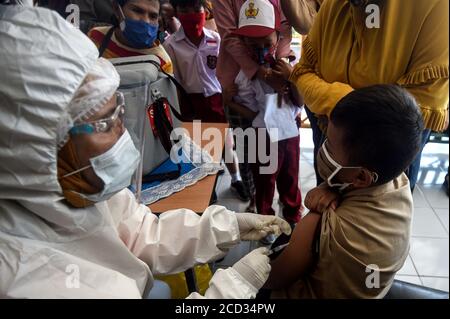 (200826) -- JAKARTA, 26. August 2020 (Xinhua) -- ein Grundschüler erhält einen Masern-Röteln-Impfstoff (MR), der von einem Gesundheitsbeauftragten während des COVID-19-Ausbruchs in Jakarta, Indonesien, am 26. August 2020 durchgeführt wird. Masern-Röteln (MR)-Impfstoffe werden Kindern als Teil des Programms der indonesischen Regierung verabreicht, um Schulkindern eine angemessene Immunisierung zu bieten. (Xinhua/Agung Kuncahya B.) Stockfoto