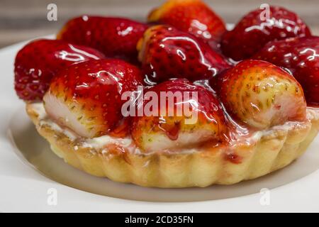 Mini-Erdbeer-Käse-Torte Nahaufnahme auf weißem Teller - fruchtige Käsekuchen Gebäck Hintergrund Stockfoto