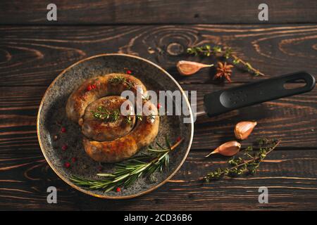 Gebratene Würstchen mit Knoblauch n der Pfanne. Auf dem schwarzen Brett. Stockfoto