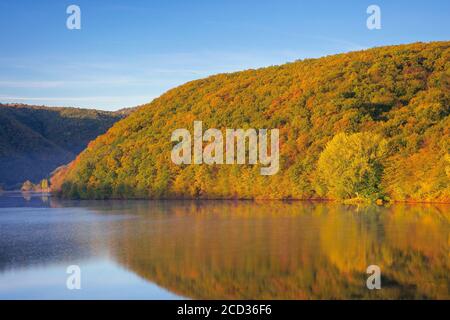 Bergsee im Wald. Bäume in bunten Blättern. Schöne Landschaft an einem sonnigen Herbstmorgen. Blauer Himmel im Wasser reflektiert Stockfoto