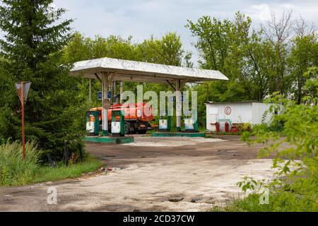 Nischni Nowgorod, Russland - 9. Juli 2020: Alte Tankstelle mit abblätternder Farbe auf Zapfsäulen mit Benzin. Ein großer Wagen füllt sich mit Kraftstoff an einem V Stockfoto