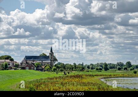 Wilsum, Niederlande, 21. Juli 2020: Blick auf das Dorf mit der Kirche auf dem Deich, mit Blick auf die Auen des Flusses IJssel Stockfoto