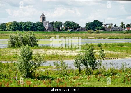 Zwolle, Niederlande, 21. Juli 2020: Blick über die Auen des Flusses IJssel in Richtung der Kirche und Windmühle des Dorfes Zalk auf der Stockfoto