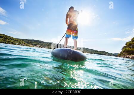 Junger Mann auf paddleboard, die Hälfte unter und über Wasser Zusammensetzung. Paddleboarding ist die moderne Art der Transport und Wasser Aktivität Sport. Stockfoto