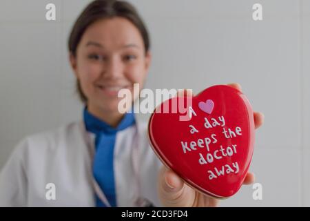 Eine Krankenschwester hält eine herzförmige Schachtel voller herzförmiger Süßigkeiten mit einem lustigen Spruch auf dem Deckel. Bilbao, Spanien Stockfoto