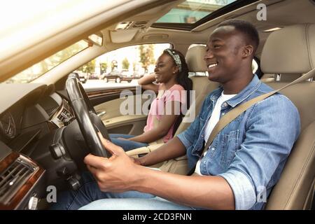 Fröhliches afroamerikanisches Paar im Auto, Seitenansicht Stockfoto