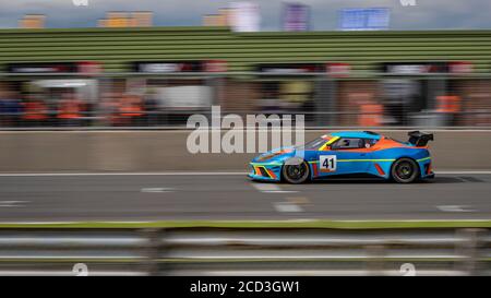 Eine Schwenkaufnahme eines blauen und orangenen Rennwagens, der eine Strecke fährt. Stockfoto