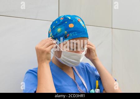 Eine junge Krankenschwester legt ihre OP-Maske an und bereitet sich auf die Arbeit vor. Stockfoto