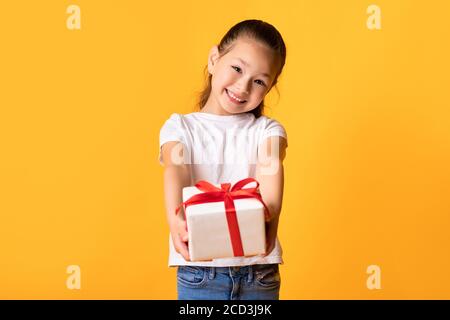 Glücklich asiatische Mädchen geben Sie Geschenk-Box im Studio Stockfoto