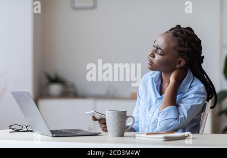 Müde schwarze Geschäftsfrau leiden unter Nackenschmerzen nach langen Tag Im Büro Stockfoto