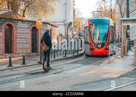 18.12.2019, Istanbul, Türkei. Ein Mann fährt auf einem Monocycle die Straße entlang. Eine Straßenbahn fährt im Hintergrund. Stadtverkehr. Stockfoto