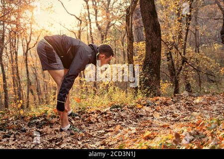 Das Konzept des gesunden Lebensstils und des Sports. Ein junger Mann in Sportkleidung ist in Stretching im Herbst Park beschäftigt Stockfoto