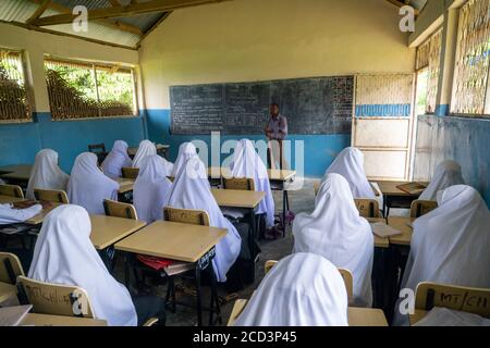 PEMBA ISLAND, SANSIBAR, TANSANIA - JANUAR 2020: Lehrer ist Tutor eine Lektion für Schulmädchen und Schuljungen im normalen Klassenraum Stockfoto