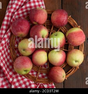 Ein Strauß rot reifer Äpfel liegt auf einer roten Serviette, Draufsicht Stockfoto