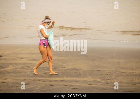 Las Palmas, Gran Canaria, Kanarische Inseln, Spanien. August 2020. Tourist mit Gesichtsmaske am Stadtstrand in Las Palmas auf Gran Canaria. Mit Covid 19 Fällen steigt auf Gran Canaria, hat die lokale Regierung verboten Joggen auf der Strandpromenade während des Tages sowie Sonnenbaden am Strand bei Flut zu verhindern, dass Gedränge. Im August wurden auf Gran Canaria mehr neue Coronavirus-Fälle registriert als in den Monaten März bis August zusammen. Mehr als 100 der neuen Fälle wurden auf eine Disco in der Hauptstadt Las Palmas zurückgeführt. Kredit: Alan Dawson/Alamy Live Ne Stockfoto