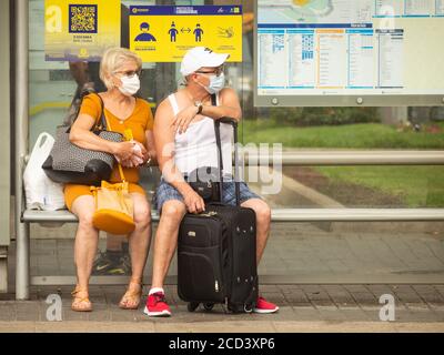 Las Palmas, Gran Canaria, Kanarische Inseln, Spanien. August 2020. Touristen mit Gesichtsmasken warten auf den Flughafenbus in Las Palmas auf Gran Canaria. Mit Covid 19 Fällen steigt auf Gran Canaria, hat die lokale Regierung verboten Joggen auf der Strandpromenade während des Tages sowie Sonnenbaden am Strand bei Flut zu verhindern, dass Gedränge. Im August wurden auf Gran Canaria mehr neue Coronavirus-Fälle registriert als in den Monaten März bis August zusammen. Mehr als 100 der neuen Fälle wurden auf eine Disco in der Hauptstadt Las Palmas zurückgeführt. Kredit: Alan Dawson/Alamy Stockfoto