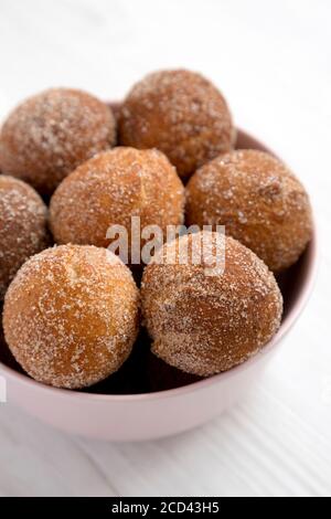 Hausgemachte gebratene Donut Löcher in einer rosa Schüssel auf einem weißen Holzhintergrund, Seitenansicht. Nahaufnahme. Stockfoto