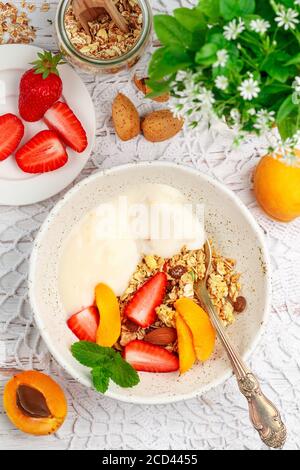 Müsli mit Fruchtjoghurt, Rosinen, Mandeln, frischen Beeren (Erdbeere, Aprikose) und Minze. Lecker und gesund hausgemachtes Frühstück, nützlich d Stockfoto