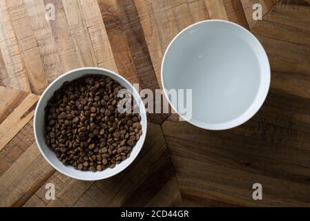 Katzenfutter Geschirr - Draufsicht auf zwei Schüsseln Trockenes Katzenfutter und Wasser stehen auf einem Holztisch Stockfoto