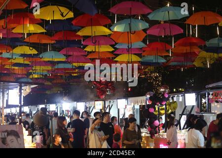 Die Menschen gehen unter einem Korridor, der mit bunten Regenschirmen geschmückt ist und den Nachtmarkt in Shenyang, im nordöstlichen Teil von Liao, ankurbeln soll Stockfoto