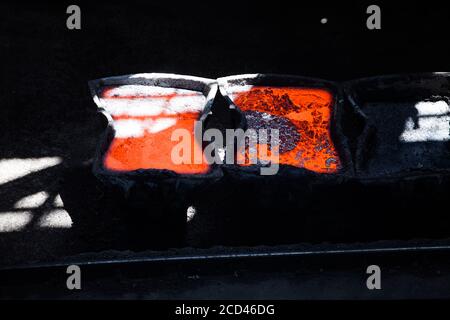 Flüssiges rotes heißes Metall im Metallurgieeimer. Metallurgische Werkshalle. Graue Schlacke auf dem Metall. Nahaufnahme des Fotos Stockfoto