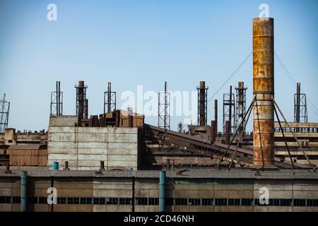 Verlassene sowjetische Metallurgie Fabrikgebäude und verrostete Kamine am blauen Himmel. Abstraktes industrielles Hintergrundfragment. Taraz Stadt. Stockfoto