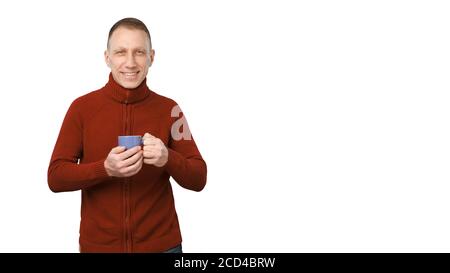 Lächelnder Durchschnittsalter Mann in roten Pullover isoliert auf weißem Hintergrund hält eine blaue Tasse Kaffee. Stockfoto