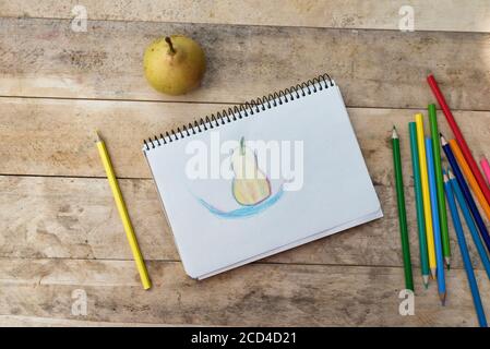 Kinderzeichnung, Birnen- und Buntstifte. Holztisch. Draufsicht Stockfoto