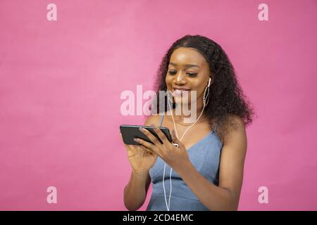 Schöne junge afrikanische weiblich beobachten ein Video mit ihrem Telefon Beim Tragen eines Ohrhörerpaares Stockfoto