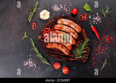 Frische, saftige Würstchen mit Tomaten, Gewürzen und Kräutern gegrillt Stockfoto