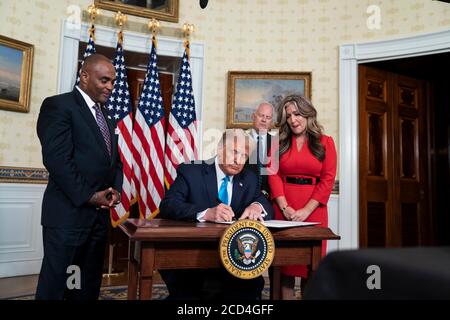 Washington, Vereinigte Staaten Von Amerika. August 2020. Washington, Vereinigte Staaten von Amerika. 25. August 2020. US-Präsident Donald Trump, zusammen mit Ex-Sträfling und Hope for Prisoners CEO Jon Ponder, Left, seine Frau Jamie, und FBI-Agent Richard Beasley, unterzeichnet eine Begnadigung für erwägen im Blue Room des Weißen Hauses 25. August 2020 in Washington, DC. Kredit: Joyce N. Boghosian/Weißes Haus Foto/Alamy Live Nachrichten Stockfoto