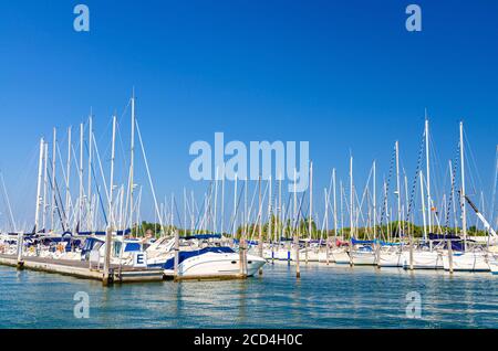 Weiße Yachten sind auf Wasser der Pier Parkplatz in Marina Hafen Hafen von Sottomarina Stadt im Sommer Tag, blauer Himmel Hintergrund, Region Venetien, Norditalien vertäut Stockfoto