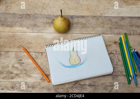 Kinderzeichnung, Birnen- und Buntstifte. Holztisch. Draufsicht Stockfoto