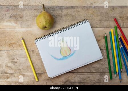 Kinderzeichnung, Birnen- und Buntstifte. Holztisch. Draufsicht Stockfoto