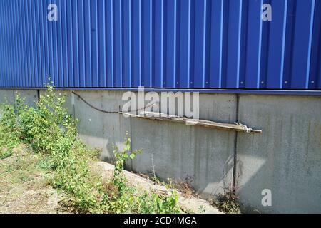 Blauer Zaun aus einem profilierten Blech auf einem Stein Wand Stockfoto